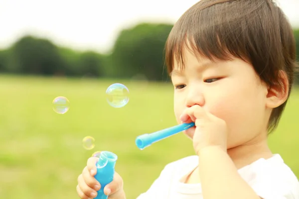Азиатский Маленький Мальчик Раздувает Мыльные Пузыри Парке Открытом Воздухе — стоковое фото