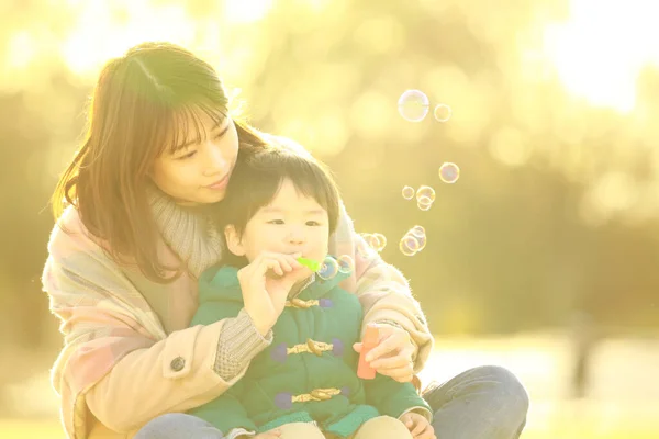 Jung Asiatisch Mutter Mit Sie Klein Junge Mit Seifenblasen Die — Stockfoto