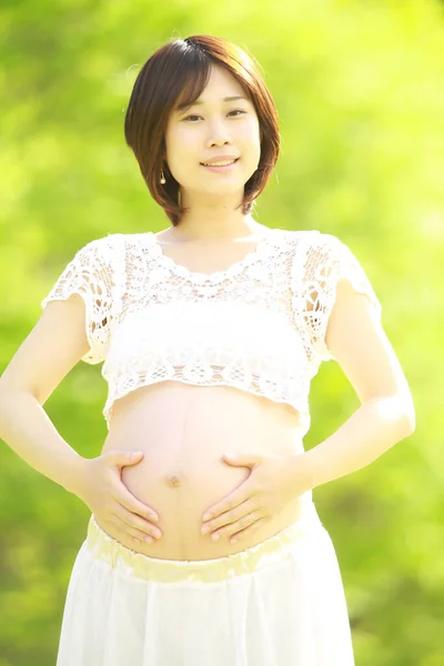 公園にいる若い美しいアジア系の妊婦は — ストック写真