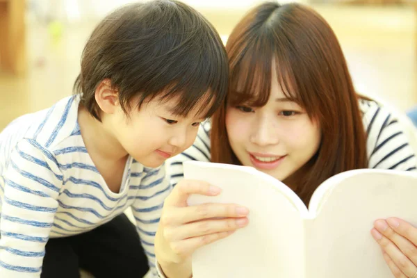 年轻妈妈和可爱的小儿子在家里一起看书 — 图库照片