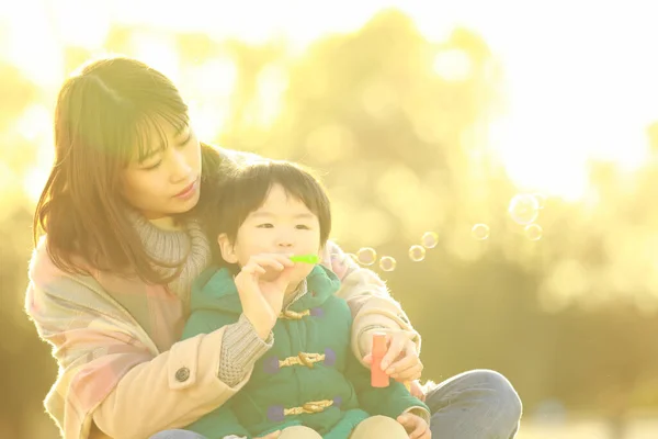Giovane Donna Asiatica Con Suo Bambino Nel Parco Soffiando Bolle — Foto Stock