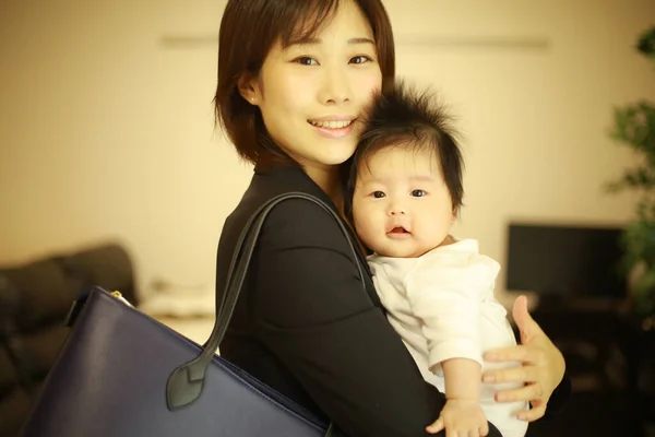 Resmi Giyinmiş Genç Asyalı Kadını Evde Küçük Sevimli Bir Bebeği — Stok fotoğraf