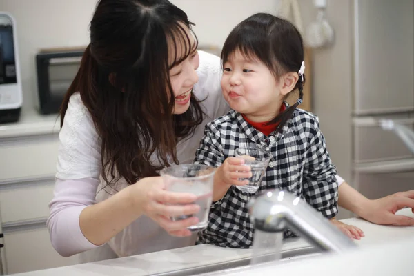 Asyalı Anne Kız Mutfaktaki Bardaklardan Içiyorlar — Stok fotoğraf