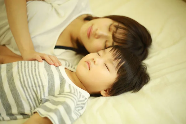 快乐的年轻母亲和小儿子躺在床上 — 图库照片