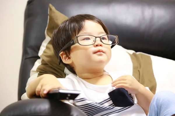 Cute Little Boy Eyeglasses Sitting Sofa Using Remote Controller — Stock Photo, Image