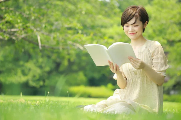 在公园看书的年轻亚洲女人的肖像 — 图库照片