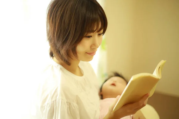 亚洲的年轻女子给她的孩子读书 — 图库照片