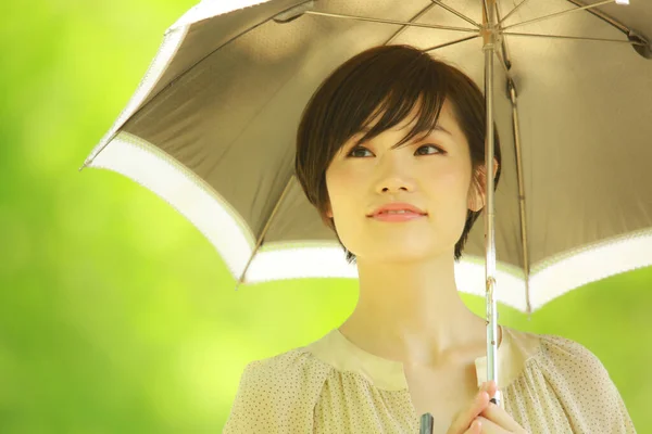 在公园里拿着雨伞的年轻亚洲女人的肖像 — 图库照片