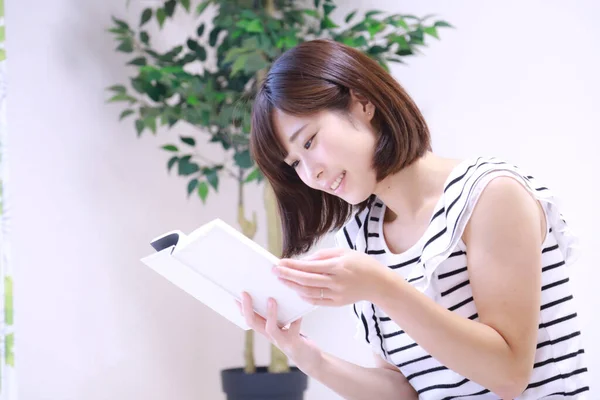 美しい若いアジアの女性は家で本を読んで — ストック写真