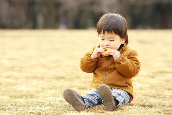 Netter Kleiner Junge Isst Donut Auf Dem Gras — Stockfoto