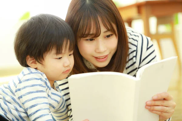 年轻妈妈和可爱的小儿子在家里一起看书 — 图库照片