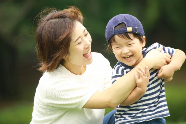 若いお母さんとかわいい小さな息子が公園で遊んでいます — ストック写真