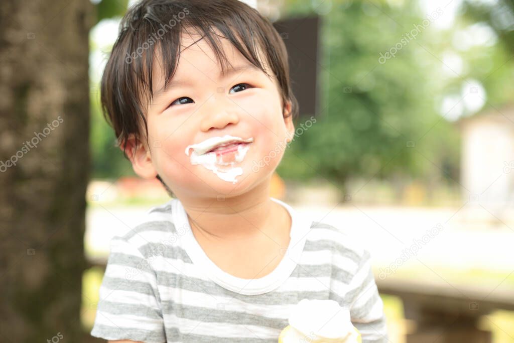 asian little boy eating ice cream  in the park outdoors 
