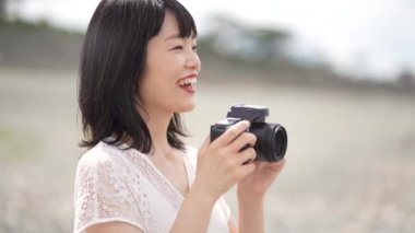 Gülümseyen Japon kadın dijital kamerayla fotoğraf çekiyor