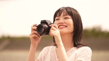Gülümseyen Japon kadın dijital kamerayla fotoğraf çekiyor