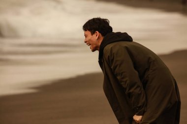 Genç Asyalı sahilde ağlıyor. 