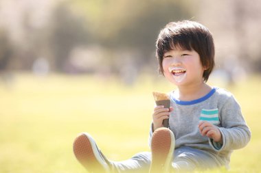 Yaz parkında yemek yiyen mutlu Japon çocuğun portresi.