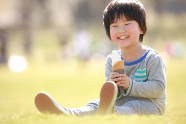 Yaz parkında yemek yiyen mutlu Japon çocuğun portresi.