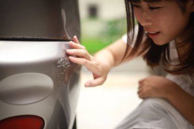 Araba çiziklerini kontrol eden kadın.