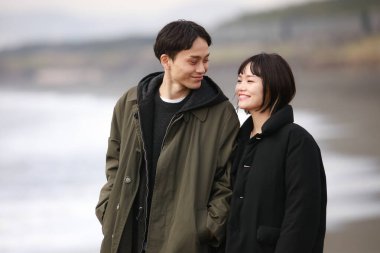 Genç bir çift sahilde yürüyor.