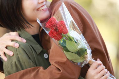 Gülleri kucaklayan genç Asyalı çift 