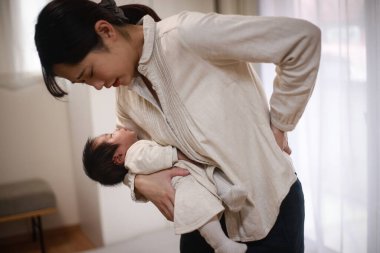 Küçük oğlunu taşıdıktan sonra genç Asyalı anne yorgun hissediyor.