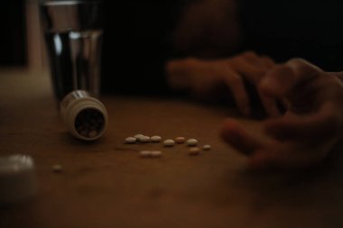 Genç adam bir sürü hap dökülmüş bir şekilde masada yatıyor. Aşırı doz uyuşturucu kavramı.