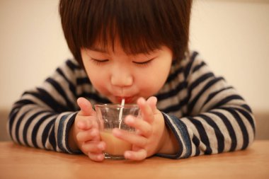 Küçük çocuk bardaktan içecek içiyor. 