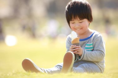 Yaz parkında yemek yiyen mutlu Japon çocuğun portresi.