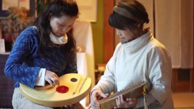 Yaşlı kadınlar geleneksel Japon müzik enstrümanı koto çalmak için alıştırma yapıyorlar.