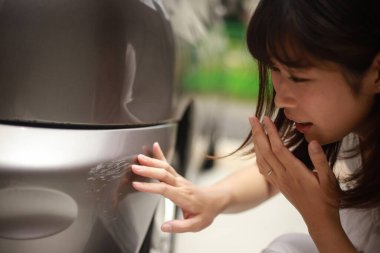 Araba çiziklerini kontrol eden kadın.