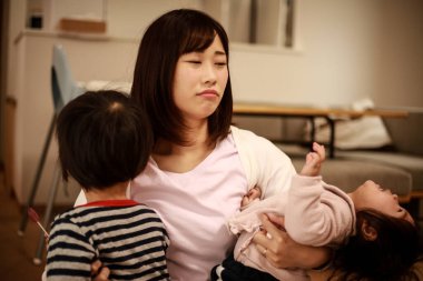 İki küçük çocuğu olan mutsuz bir Asyalı kadın.