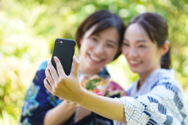 Kimonolu mutlu Asyalı kadınlar sokak yemekleriyle selfie çekiyorlar.