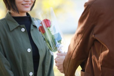  Asyalı adam kadınlara çiçek sunuyor. 