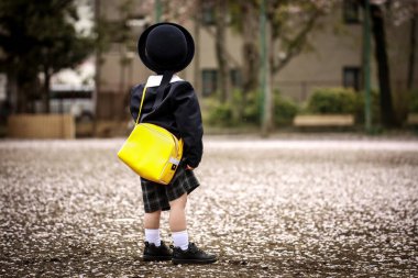 Sarı çantalı çocuk parkta yürüyor.