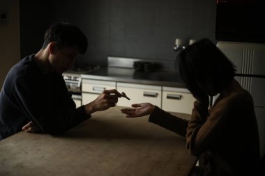 Mutfakta anahtarı paylaşan üzgün bir çift.