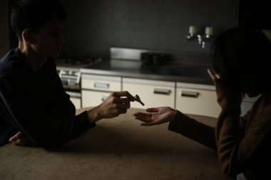 Mutfakta anahtarı paylaşan üzgün bir çift.