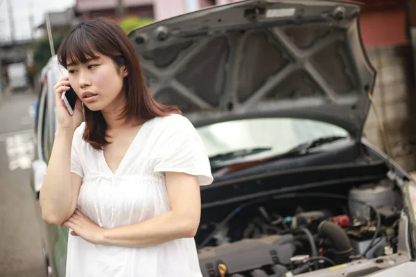 Stresli Asyalı Kadın Dışarıda Kırık Bir Arabanın Yanında Telefonla Konuşuyor — Stok fotoğraf