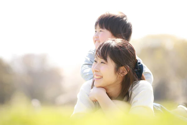 Mutlu Asyalı anne ve küçük oğlu yaz günü parkta dinleniyor. 