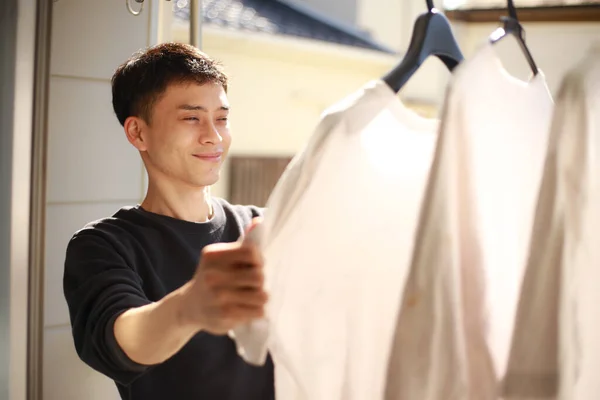 Mladý Asijský Muž Hledá Čerstvé Bílé Tričko Balkóně — Stock fotografie