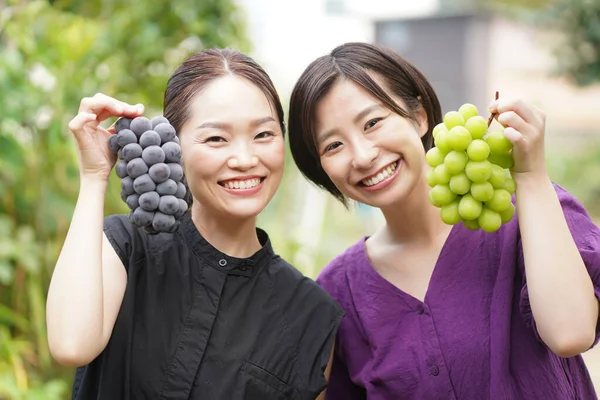 Unga Och Leende Japanska Kvinnor Som Håller Färska Druvor Händerna — Stockfoto