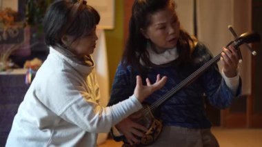 Kadınlar geleneksel Japon müzik enstrümanı Sanshin 'de çalmak için pratik yapıyorlar.