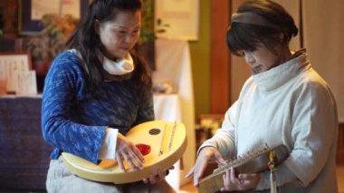 Yaşlı kadınlar geleneksel Japon müzik enstrümanı koto çalmak için alıştırma yapıyorlar.