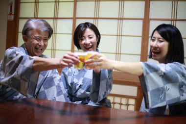 Kimonolu mutlu Asyalı arkadaşlar Japon restoranında bira içiyorlar.