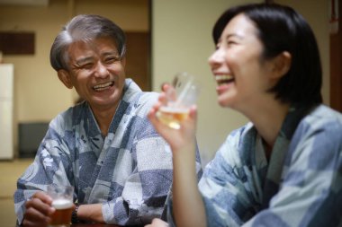 Kimonolu mutlu Asyalı arkadaşlar Japon restoranında bira içiyorlar.