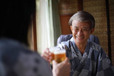 Kıdemli Asyalı adam karısıyla bira içiyor.