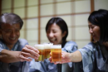 Kimonolu mutlu Asyalı arkadaşlar Japon restoranında bira içiyorlar.