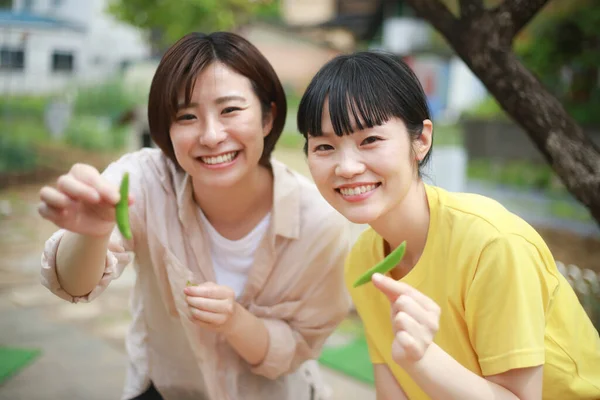 Leende Unga Asiatiska Kvinnor Håller Ärtor Skida Utomhus — Stockfoto