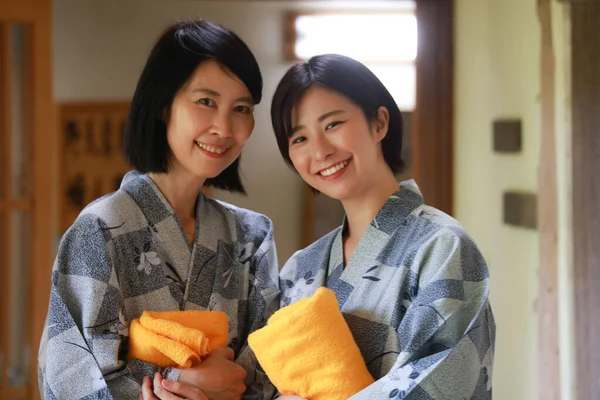 黄色のタオルを着た幸せと笑顔の日本人女性が温泉浴を準備 — ストック写真