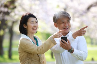 Parkta el kol hareketi yapan Asyalı erkek ve kadın. 